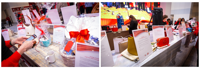 1st image: Chicago Go Red woman attendee’s hands holding mobile phone in front of auction display signs and packages. There are display signs for two wrapped auction item baskets sitting on top of counter. 2nd image: Multiple auction display signs and packages on top of counter. A red Tory Burch purse is displayed.